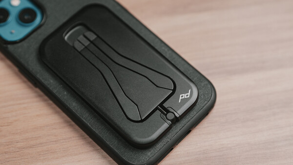 Black smartphone case with integrated magnetic stand mounted on a blue-trimmed phone.