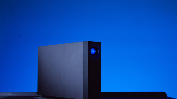 Black desktop computer tower with illuminated blue power button against deep blue gradient background.