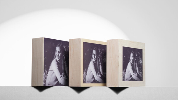 Three wooden display boxes arranged in a row, each featuring the same black and white portrait photograph of a woman.