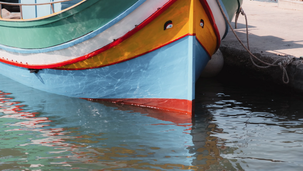 Colorful fishing boats with blue, yellow, and red hulls moored in shallow turquoise water.