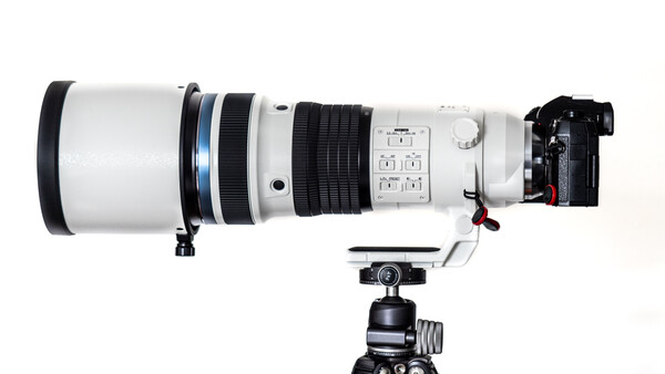 Large telephoto lens mounted on a ball head tripod with camera body attached on the right side.