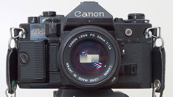 Canon F-1 35mm SLR camera with Canon FD 50mm f/1.4 lens mounted, shown from front against white background.