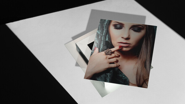 Composite photograph showing layered portrait prints arranged at angles on white paper with dramatic lighting.