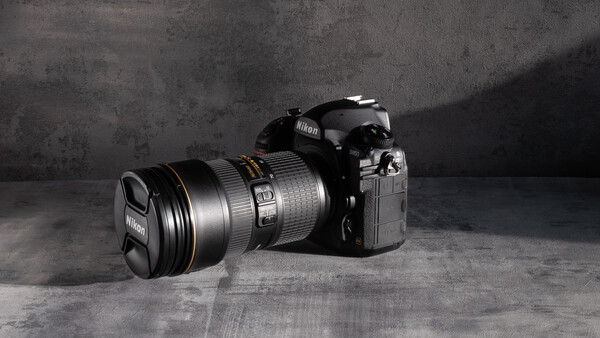 Nikon DSLR camera with attached telephoto lens on textured concrete surface.