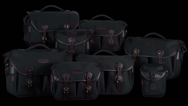 Collection of nine black camera bags and cases with brown leather accents arranged on a black background.