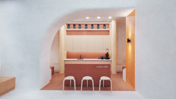 Interior rendering of a minimalist coffee shop with terracotta tile flooring and three white stools at the counter.