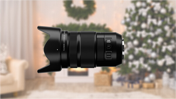 Black telephoto lens with lens hood against blurred holiday interior background.