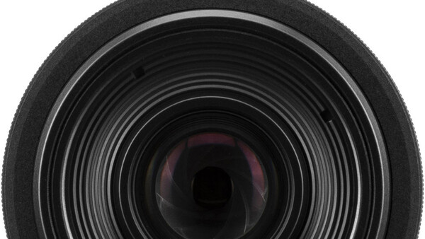 Close-up view of camera lens front element with concentric glass rings and internal reflections.