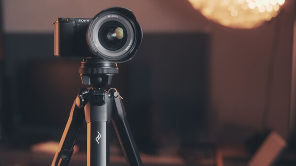 Sony mirrorless camera mounted on tripod with wide-angle lens, warm golden hour lighting in background.
