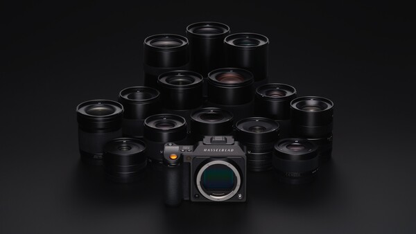 Medium format camera body surrounded by approximately 14 black prime lenses arranged in a pyramid formation.