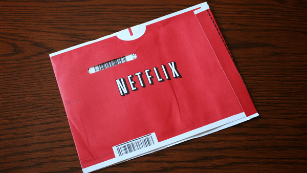 Red Netflix DVD envelope with white logo and barcode labels on wooden surface.