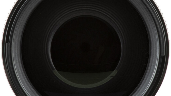 Close-up view into the barrel of a camera lens showing concentric glass elements and internal aperture mechanism.