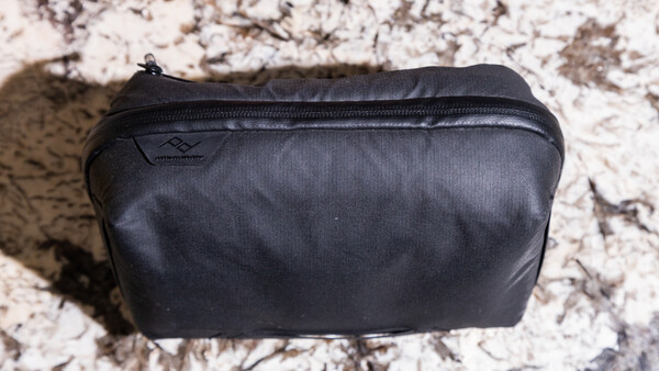 Black nylon toiletry bag with zipper closure on textured granite surface.