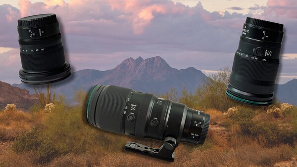 Three telephoto lenses displayed against a desert landscape with mountains and sunset sky.