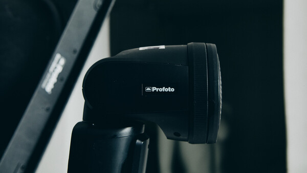 Profoto studio flash head mounted on a light stand against a dark background.