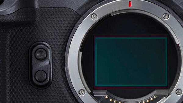 Camera body with open sensor showing cyan-tinted imaging surface and control buttons on textured grip.