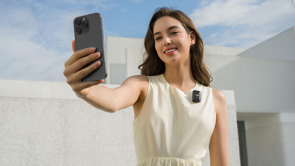 Woman holding smartphone at arm's length to take a selfie outdoors.