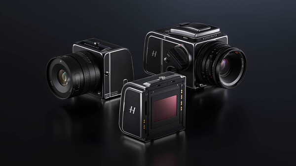 Three medium format film cameras with interchangeable lenses arranged on a dark surface.
