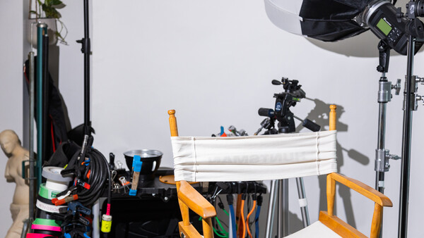Photography studio setup with lighting equipment, reflectors, and production gear arranged on tables.