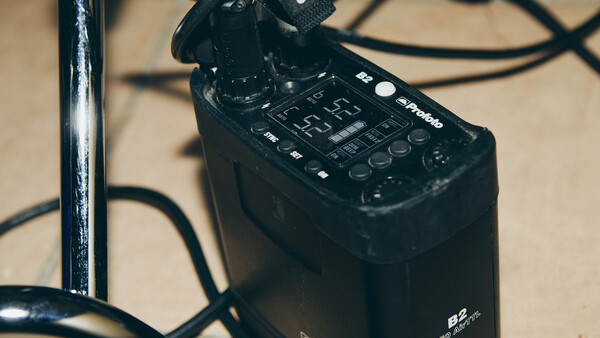 Black audio recorder with control panel and microphone attachment on beige surface with cables.