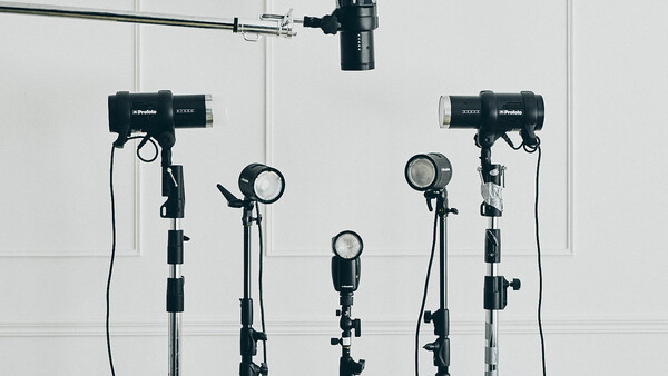 Professional studio lighting setup with five mounted light fixtures and overhead rigging against white walls.