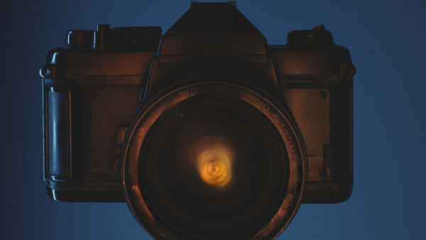 Illustration of a vintage film camera with glowing lens against a blue background.