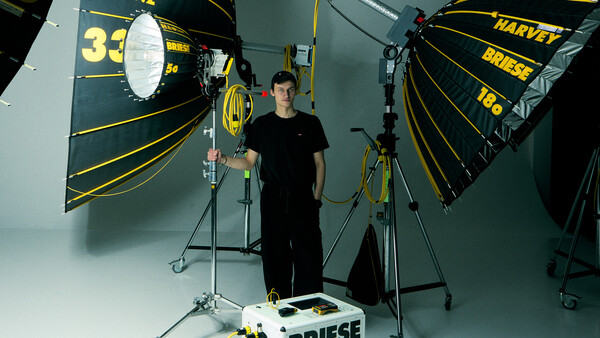 Professional film production lighting setup with large parabolic reflectors and a cinematographer in a controlled studio environment.
