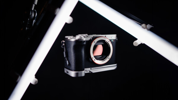 Mirrorless camera body with open shutter displayed against black background with white frame border.