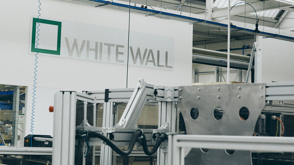 Industrial manufacturing facility with White Wall branding visible on white wall signage above machinery.