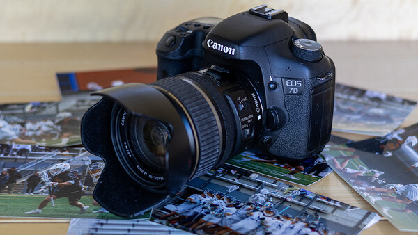 Canon EOS DSLR camera with attached lens resting on printed photographs.