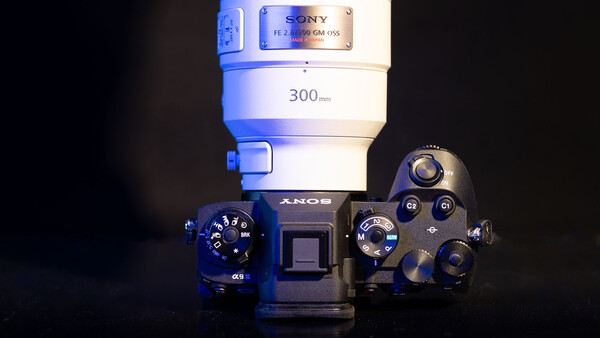 Sony α5000 mirrorless camera with 300mm lens mounted, photographed against dark background with dramatic blue-tinted lighting.