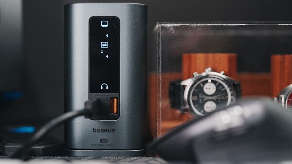 Baseus power strip with touch controls and orange digital watches displayed in background.