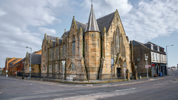 Stone Victorian-era church with Gothic spires at a street corner intersection.