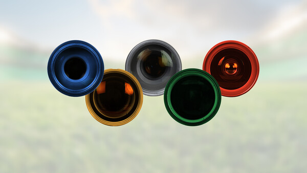 Five colored rings arranged in Olympic symbol pattern against blurred background.