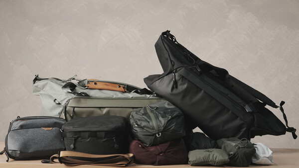 Collection of camera bags and travel gear organized in a flat lay arrangement against a neutral background.