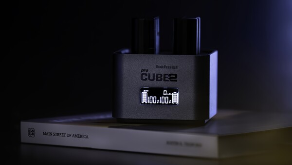 Roland Cube2 amplifier displaying digital clock on dark surface with book beside it.