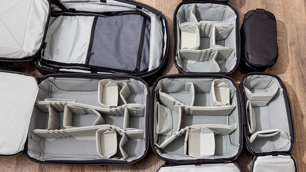 Collection of open camera equipment organizer cases with customizable padded dividers on wooden surface.