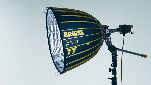 Briese Focus.2 77 parabolic softbox mounted on a light stand against a light sky backdrop.
