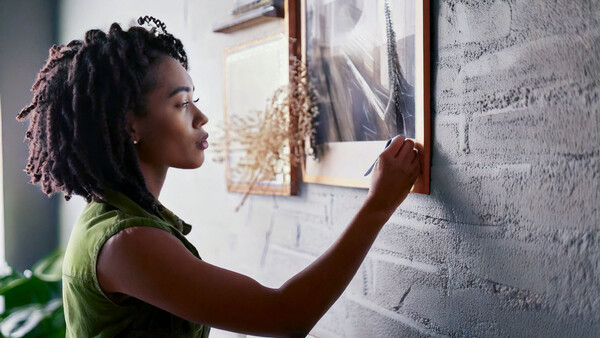 Woman in green sleeveless top examining architectural drawings or plans on a textured wall surface.