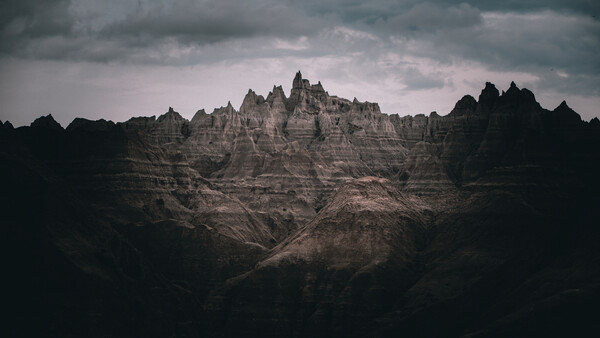 Dramatic badlands landscape with distinctive peaked formations rising against stormy sky.