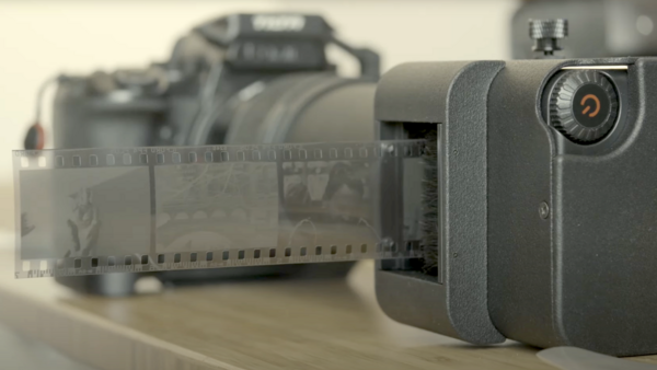 Compact digital camera next to 35mm film roll and vintage film camera in soft studio lighting.
