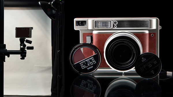 Vintage instant camera in red and chrome with accessories on reflective black surface.