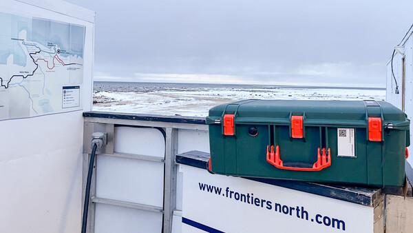 Green and red toolbox on a white van with coastal landscape visible in background.
