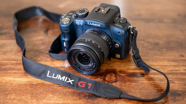 Panasonic Lumix G1 mirrorless camera with attached lens and strap on wooden surface.