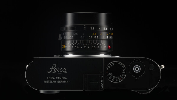 Top-down view of a Leica rangefinder camera with mounted lens against a black background.