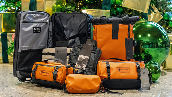 Collection of orange and black camera bags and cases arranged with luggage on a marble surface.