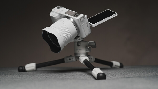 White mirrorless camera with articulating screen mounted on tripod with flexible legs.