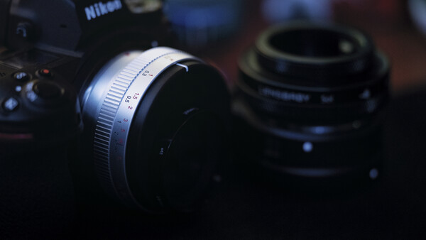 Nikon camera with silver lens in sharp focus, additional lens blurred in background.