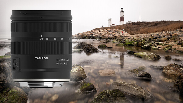 Tamron 11-25mm f/2.8 lens displayed against a coastal landscape with rocky shoreline and lighthouse.