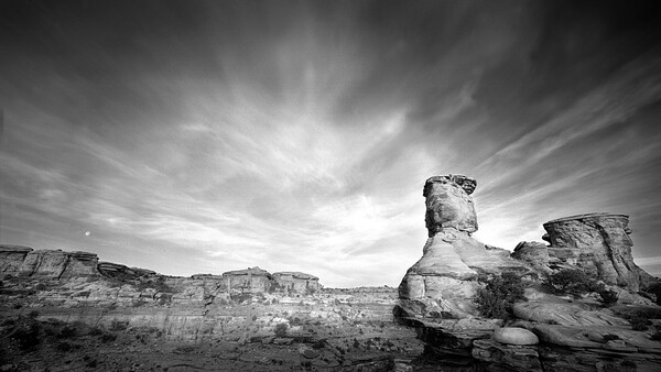 Weathered rock formations rising from an arid desert landscape beneath a dramatic cloudy sky.